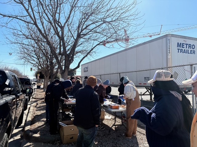 People gathered around outdoor tables with food and supplies